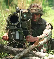 Colour photograph of a marine with an anti-tank weapon pointed at the camera.