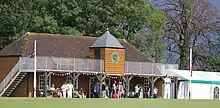 Cricket pavilion with players watching on a summers day