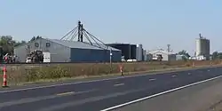 Metal building with "Buda Corn & Storage" on side; large metal tanks; grain elevators