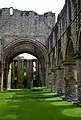 View of the church interior, with the triple window in the eastern wall of the chancel, viewed through the arches supporting the central tower.