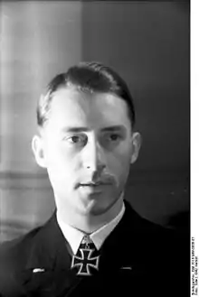 A young man with a black uniform and an Iron Cross at his neck; his hair is combed back.