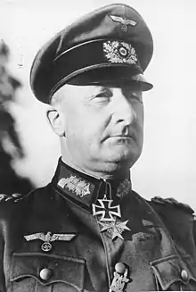 A man wearing a military uniform and peaked cap with two military orders at the front of his uniform collar.