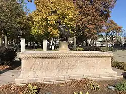 A large, rectangular, pink granite base with a smaller, aged bronze state of a boy and turtle sitting in the center of the base.