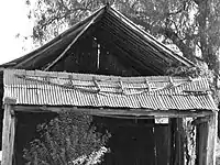 Fig. 9: The northern gable-end was fashioned by nailing sheets of galvanized iron onto a sub-frame. Insecurely fastened to the main structure, it has fallen out.