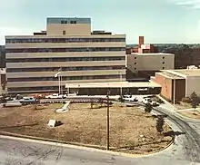 Aerial photograph of a 1960s modern tan building with dark horizontal stripes of windows