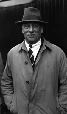 A smiling man with a white moustache and a fedora