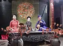 Man on the right is playing the đàn đáy which is an important part of ca trù