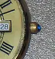 A round sapphire cabochon on the crown of a men's dress watch.