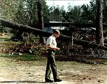 Governor Carroll walking among downed trees