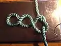 Step 2 of tying Cross constrictor knot: simple knot, sides pulled to form 3 loops