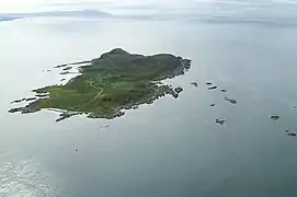 A green island sits in a clam sea. There are numerous small islets in the surrounding waters.