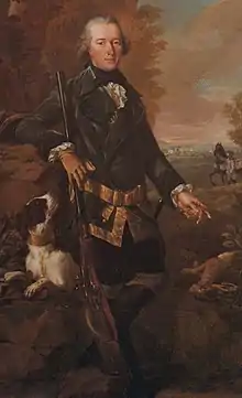 Full length portrait of a man in a dark coat holding a rifle about four and a half feet long with his dog