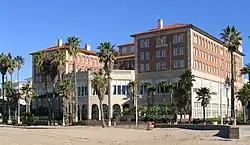 A large and elegant pink-and-tan building with several archways and two large wings on either side.