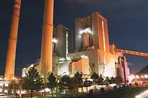 two tall chimneys and large buildings lit up at night