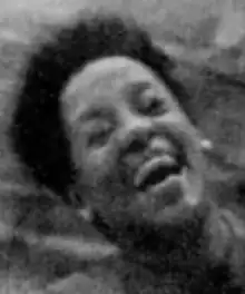 An African American woman with short hair, head thrown back and mouth open in a joyful expression.