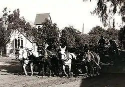 Central Ave, Sierra Madre CA in 1904. A mule team is grading the Ave for the installation of the 1905 Pacific Electric street car, in front of Sierra Madre Memorial Park, the background is the Old North Church with the original barn roof bell tower.