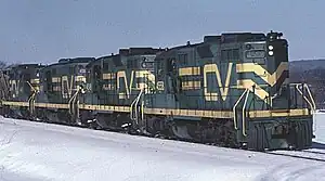 Four green and yellow locomotives pulling a train.