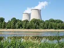 Nuclear power plant in Cattenom, France four large cooling towers expelling white water vapour against a blue sky