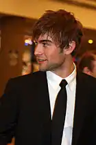 A man with slightly spiked brown, looking sharply to his right, wearing a suit and tie.