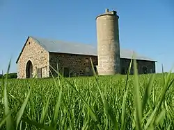 Image 34A stone barn built for cows in Wisconsin. The circular silo was used to store feed. (from History of Wisconsin)