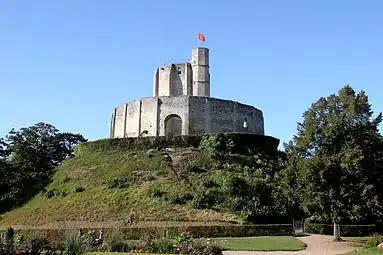 A small castle comprising a round keep surrounded by a tall encircling wall on top of a man-made hill