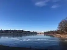 Ice on surface of the reservoir in January. View across of trees and stadium.