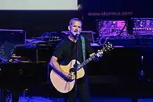 An older man playing an acoustic guitar