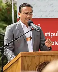 Hoskin standing a a podium, speaking into a microphone