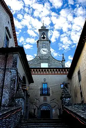 stairs to a small courtyard, at the back a building with a bell-tower and clock