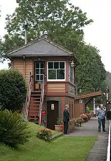 Wooden signal box next to railway platform decorated with flowers.