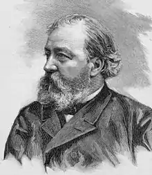 Head and shoulders of a middle-aged man wearing a coat, facing his right.  His receding hair is swept back and his beard is unruly, obscuring his mouth and chin.