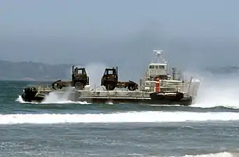 A US Army LACV-30 (Lighter Air Cushion Vehicle - 30 Ton) hovercraft transporting ground-support military equipment to the shore in 1986.