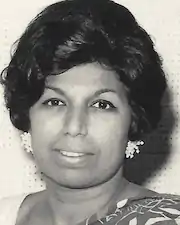 A South Asian woman with short dark hair in a bouffant set; she is wearing white beaded earrings and a sari.