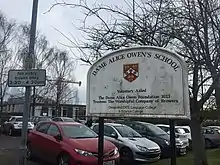 A sign at the front of the school which includes the text "Designated DfEE Language College & Science College"