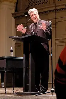 A man standing at a lectern, delivering a speech