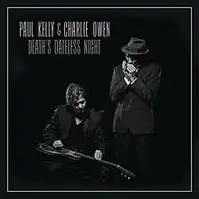 The artists' names are written in white on black background at top left. Album title is below. Main image show two men: the one at left is sitting to play a lap steel guitar; the other man is standing to play a harmonica