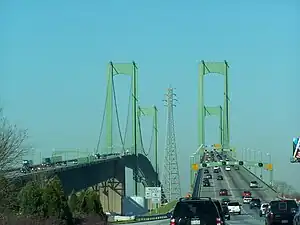 A congested divided freeway approaching a green twin-span bridge