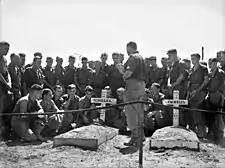 A group of men in military uniform gathered around a grave.