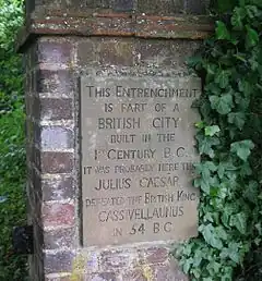 A commemorative plaque in a brick pillar surrounded by woods