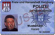 An identity card with a picture, the coat of arms of Hamburg, the police star of Hamburg and the German word sample written across.