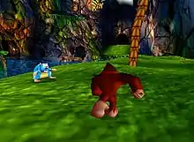 A brown gorilla runs across a green expanse of blurry green. A palm tree grows in the back right corner and a dark jungle background shows in the distance.