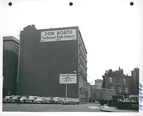 Large, windowless wall with cars parked