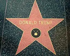 A red star with a bronze outline and "Donald Trump" and a TV icon written on it in bronze, embedded in a black terrazzo sidewalk