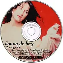 A photo of De Lory against a red background is present atop a compact disc.