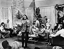 The Doodletown Pipers (as themselves) with Leslie Uggams (as herself), Robert Morse (as Robert Dickson) and E. J. Peaker (as Gloria Quigley Dickson) in "Our First Christmas" (the thirteenth episode of the 26-episode 1960s American musical comedy television series That's Life)