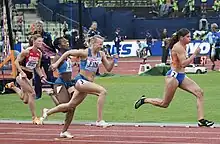 Photo of Zoë Sedney and three other competitors sprinting during a relay race