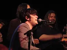 Ed Harcourt performing, surrounded by individuals