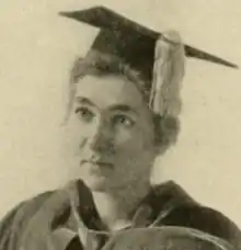 A white woman in academic robe and mortarboard cap