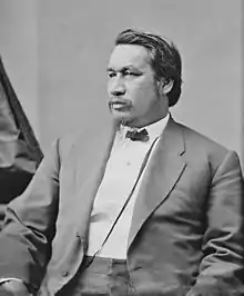 Formal photographic portrait of a sitting mustached man