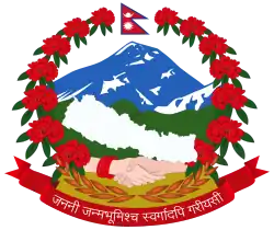 In the background, blue-white snowy himalayas, green forested hills and yellowish fertile plains from top to bottom; in the foreground, two male and female hands joined and a plain white map of Nepal, supported by a wreath of red rhododendrons, seven on each side, with the flag of Nepal at the crest, and at the bottom, the motto of Nepal in Devanagari script